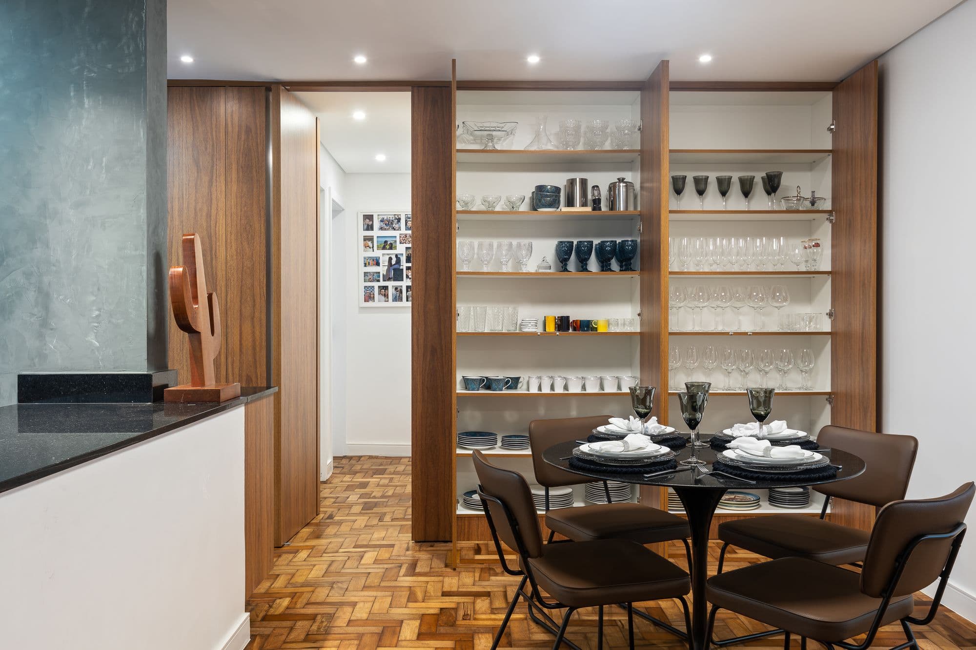 Sala de jantar com painel de madeira aberto revelando a cristaleira