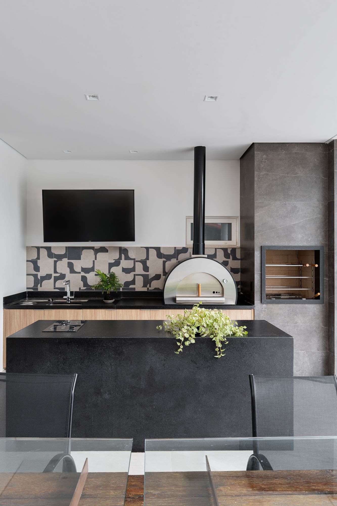 Área gourmet com forno de pizza, churrasqueira e marcenaria clara